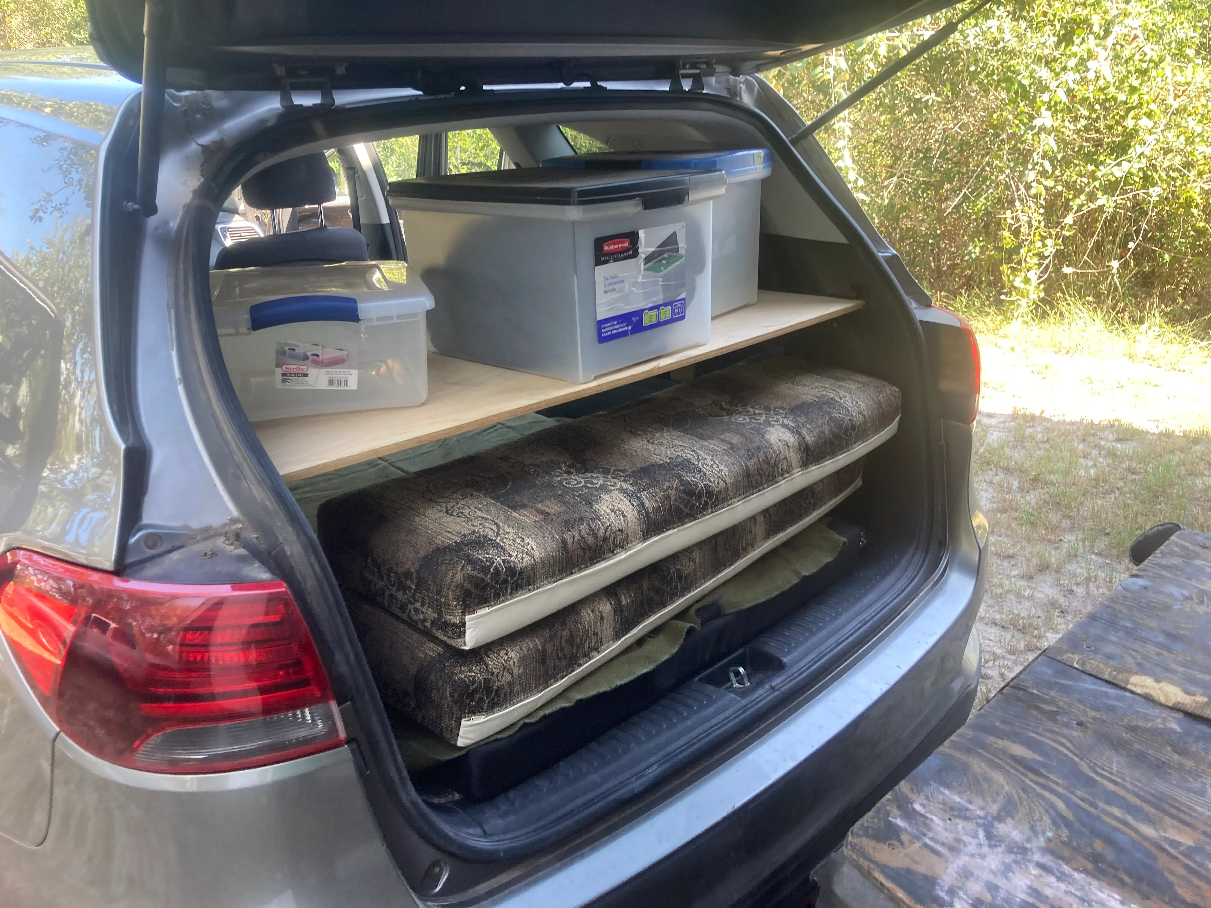 The sleeping setup — foam on the floor, feet under the shelf