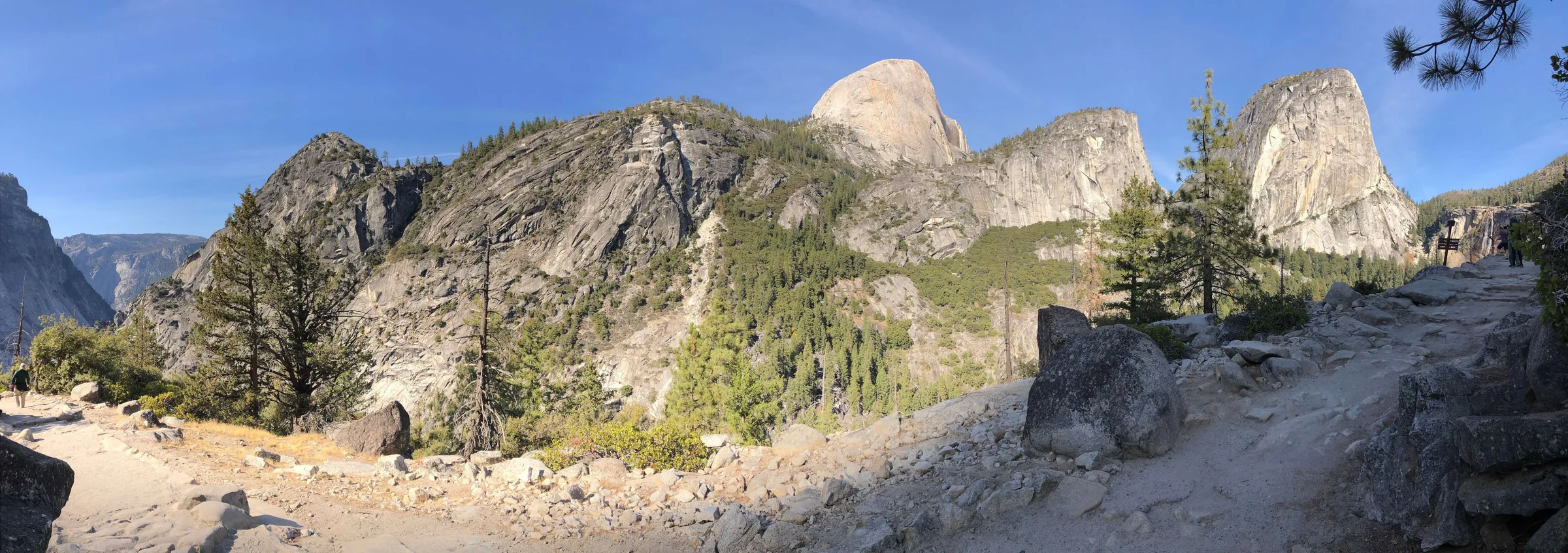 Half Dome from the high trail — the valley spreading out below, the full Sierra Nevada range behind it.