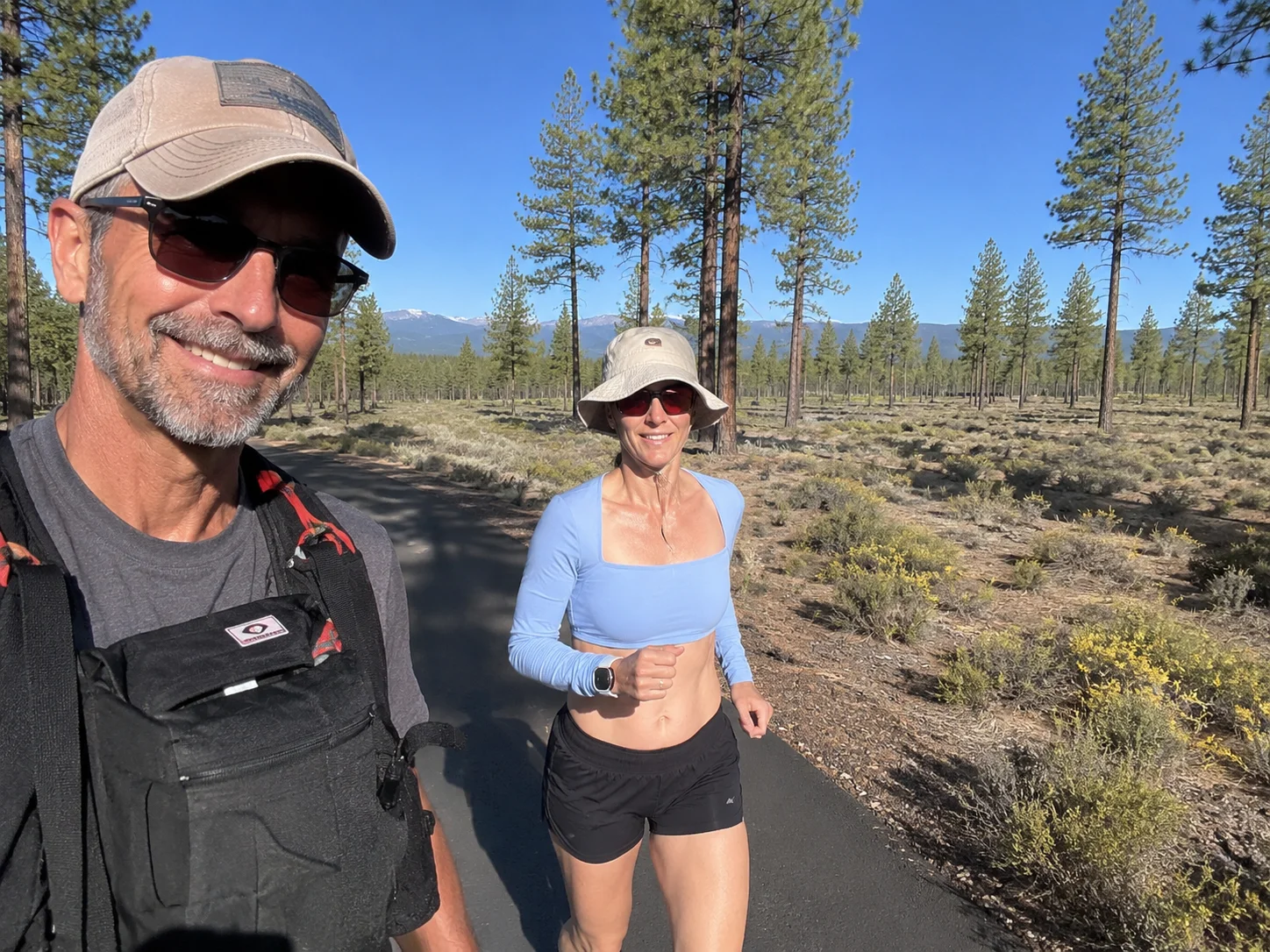 Tortuga and Polly running Peterson Ridge Trail — open ponderosa forest, Cascade peaks visible through the trees, Sisters half a mile north