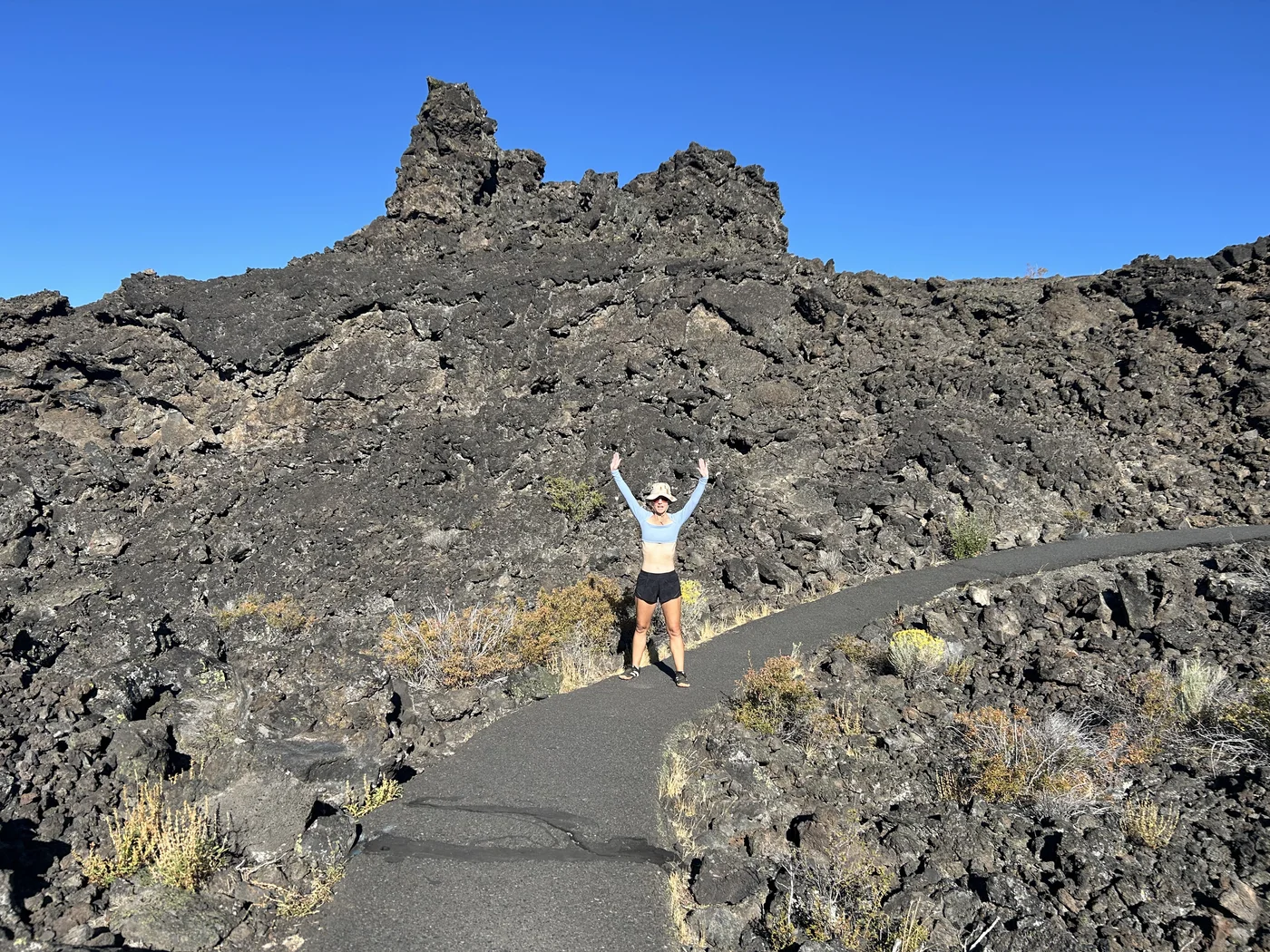 Polly on the Big Obsidian Flow trail at Newberry Volcanic National Monument — lava formations towering on both sides, the scale is hard to believe