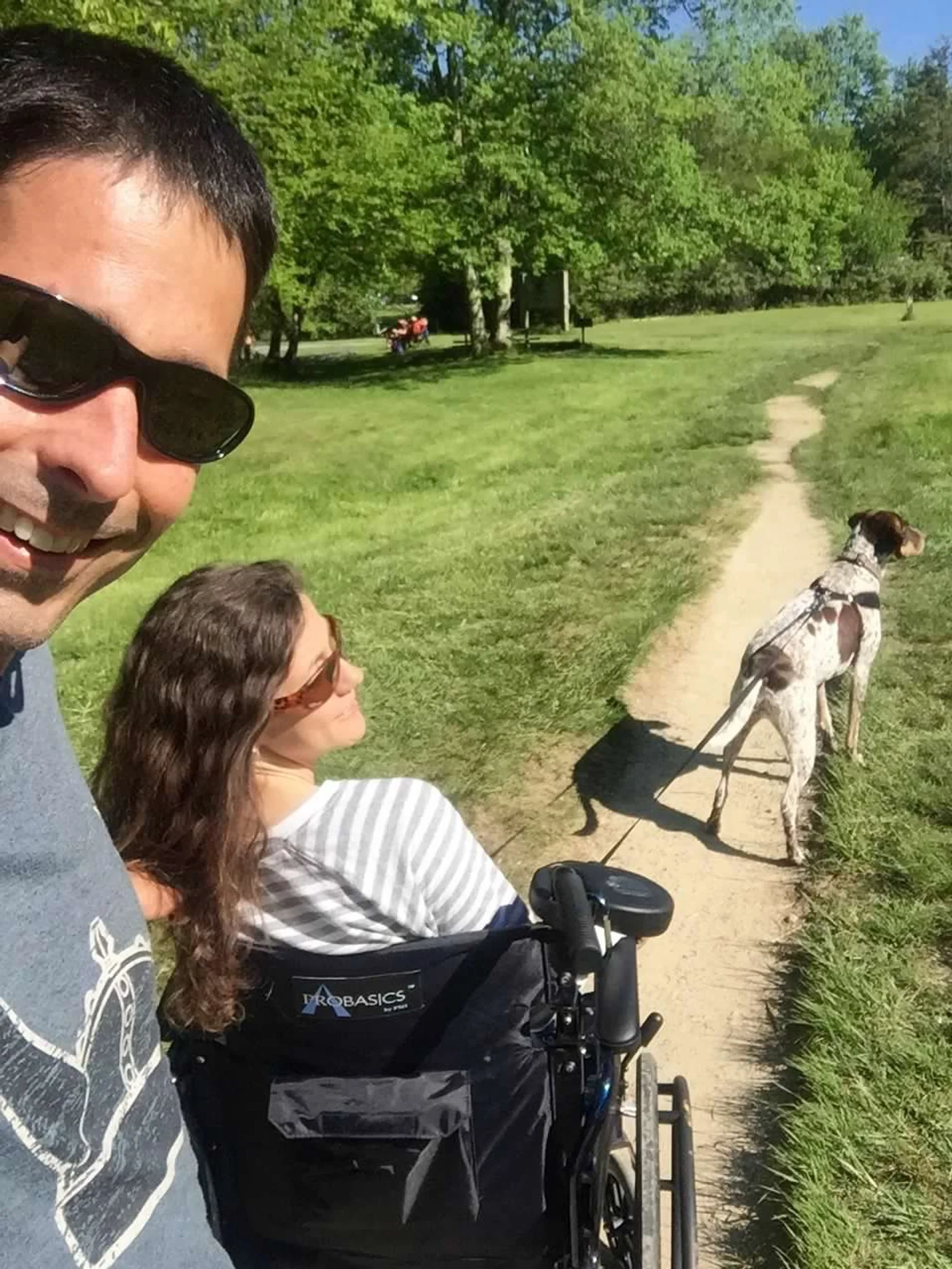 Polly in the wheelchair on trail — Lacy doing her best to help, whether help was wanted or not