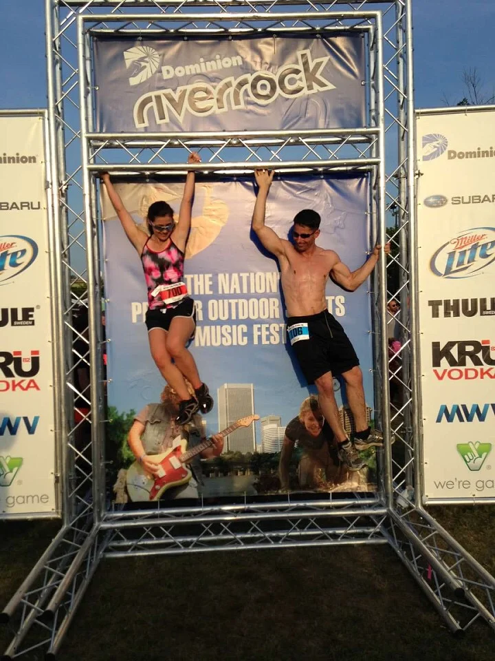Tortuga and Polly hanging playfully from an event banner at the Dominion Riverrock festival, Richmond, Virginia